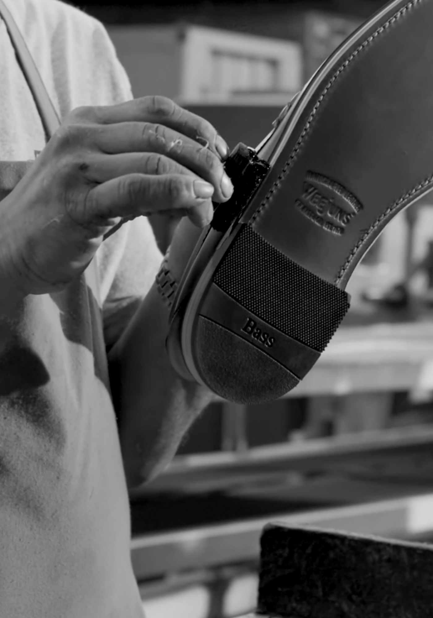 Close-up of a craftsman hand-finishing a G.H. Bass Weejun loafer, highlighting the embossed “Bass” logo and precision leather craftsmanship.