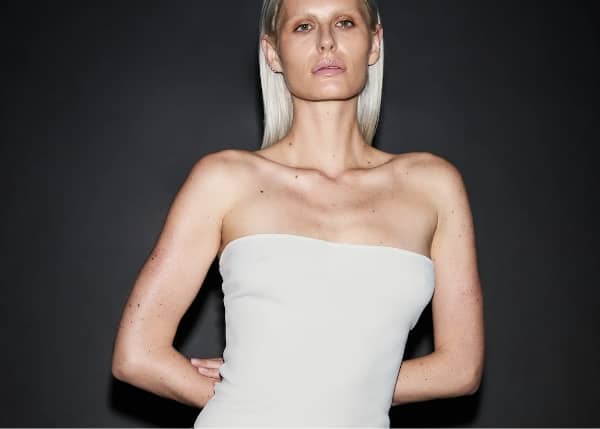 Entire Studios editorial — model in minimalist white strapless top against dark backdrop, embodying sculptural simplicity and contemporary streetwear minimalism.