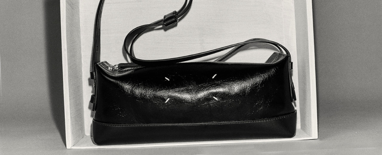 Maison Margiela black leather shoulder bag defined by minimalist construction, subtle stitching details, and the house’s signature understated approach to contemporary luxury.