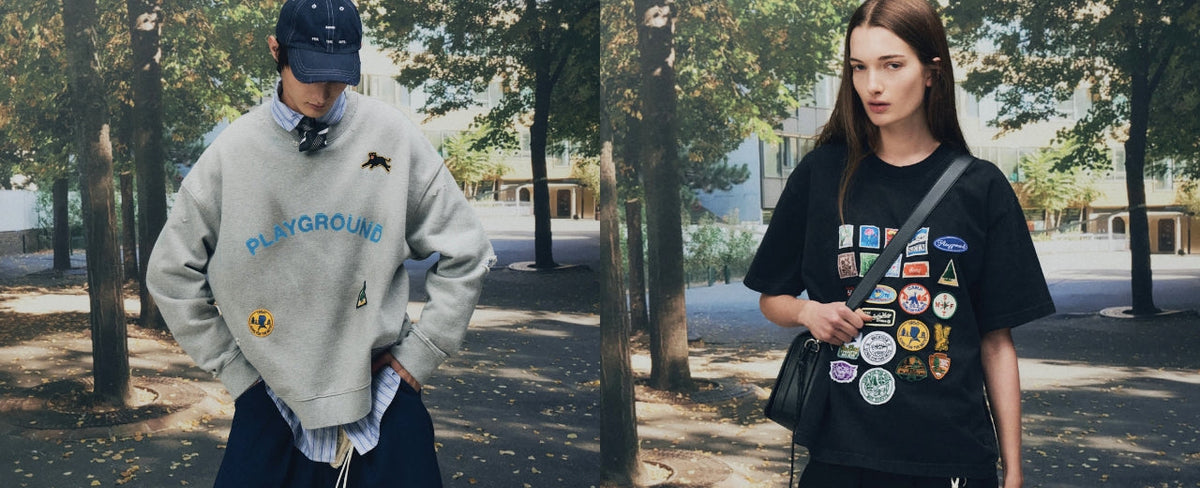 Song for the Mute editorial campaign featuring oversized grey Playground sweatshirt and black graphic patch T-shirt, styled with relaxed streetwear and accessories in a tree-lined urban setting.