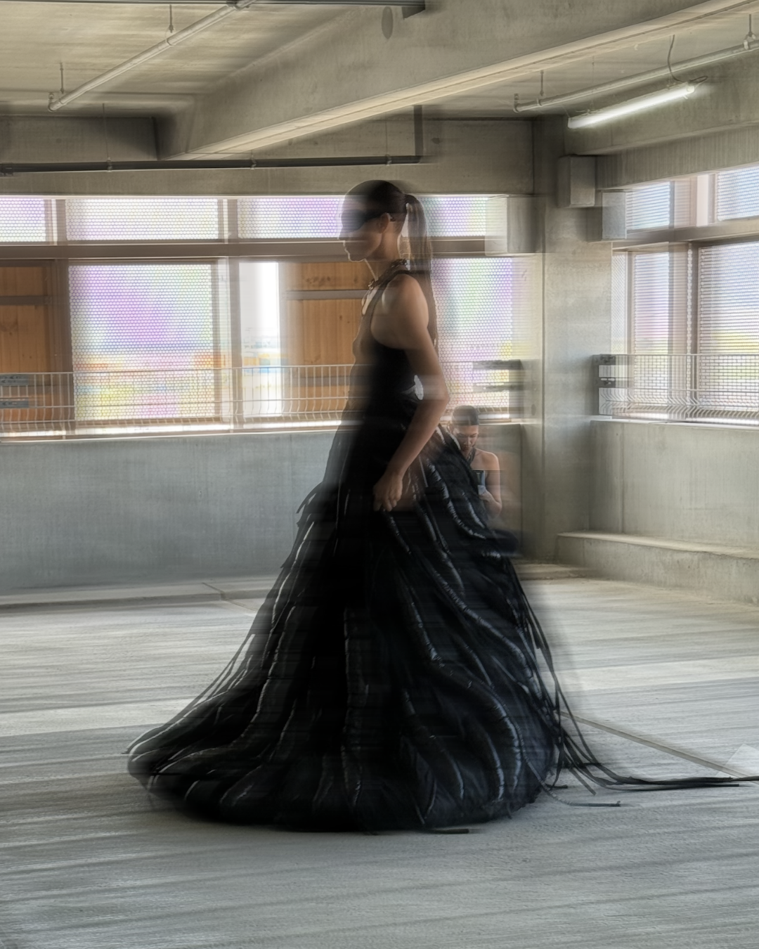 Han Kjøbenhavn runway — model in voluminous black sculptural gown with sheer layered textures, captured in blurred motion for a futuristic avant-garde silhouette.