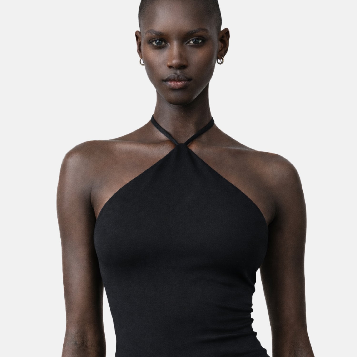 Female model wearing a black Jacquemus halter bodysuit from ELLIS ROSCH Women’s New Arrivals, styled with a minimal, sculpted silhouette. The top features a high neckline with thin straps that wrap around the neck, creating a clean, open shoulder line and a sleek, form-fitting shape. Shot against a neutral studio background, the image emphasizes the garment’s smooth texture, precise tailoring, and modern elegance. The look reflects Jacquemus’ signature approach to refined minimalism—sensual, architectural,