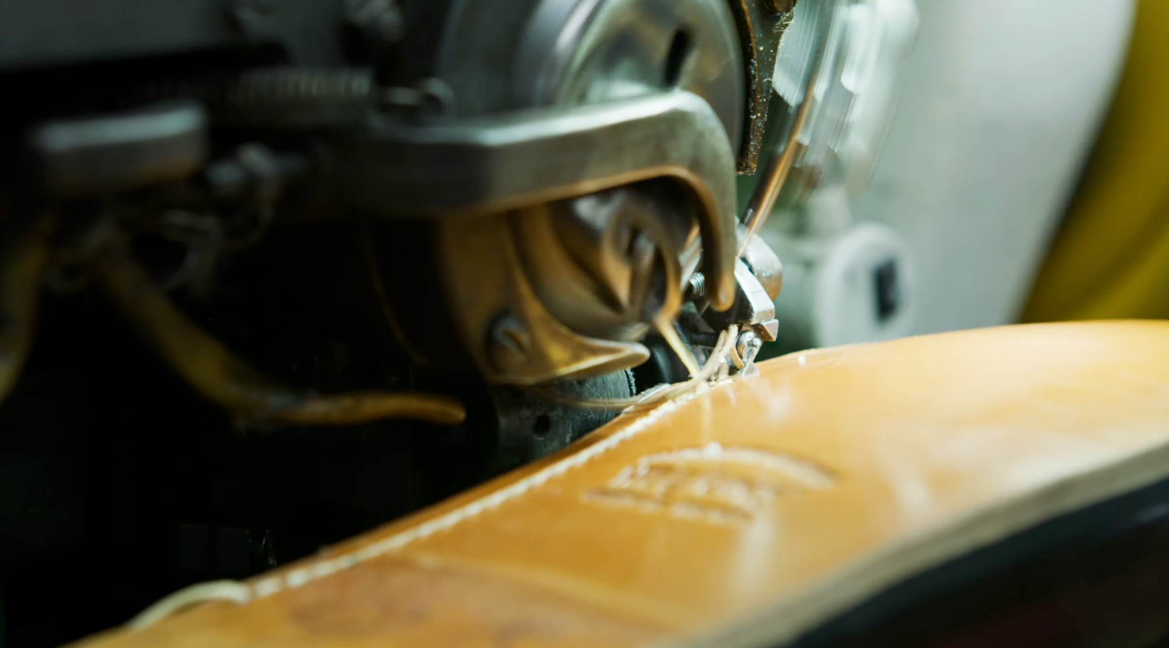 Detailed macro view of stitching on a G.H. Bass Weejun loafer, showing traditional moccasin construction and fine leather detailing under a sewing machine.