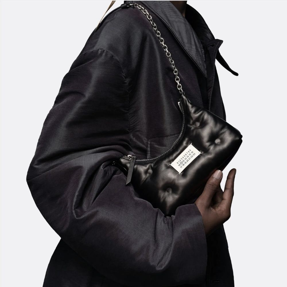 Maison Margiela black leather shoulder bag with chain strap and signature numeric label, expressing the house’s minimalist design language, understated luxury, and contemporary craftsmanship.