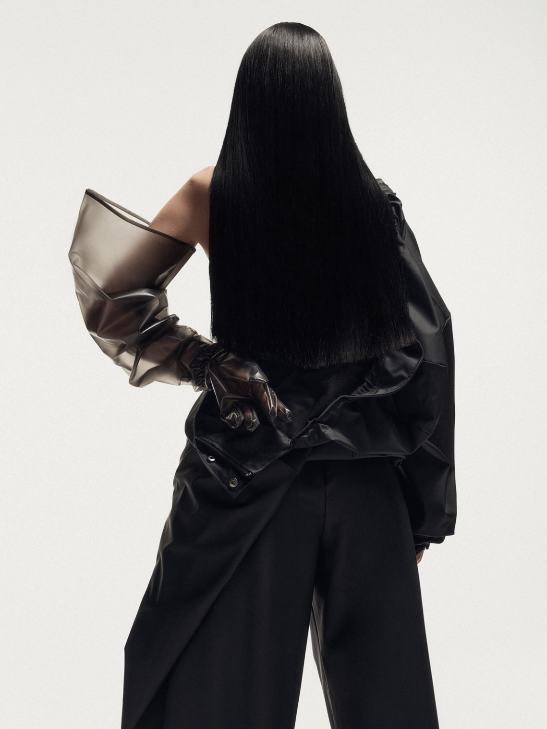 RAINS editorial look — model in sculptural black rainwear with oversized sleeves and wide-leg trousers, capturing Scandinavian minimalism and waterproof design as high fashion.