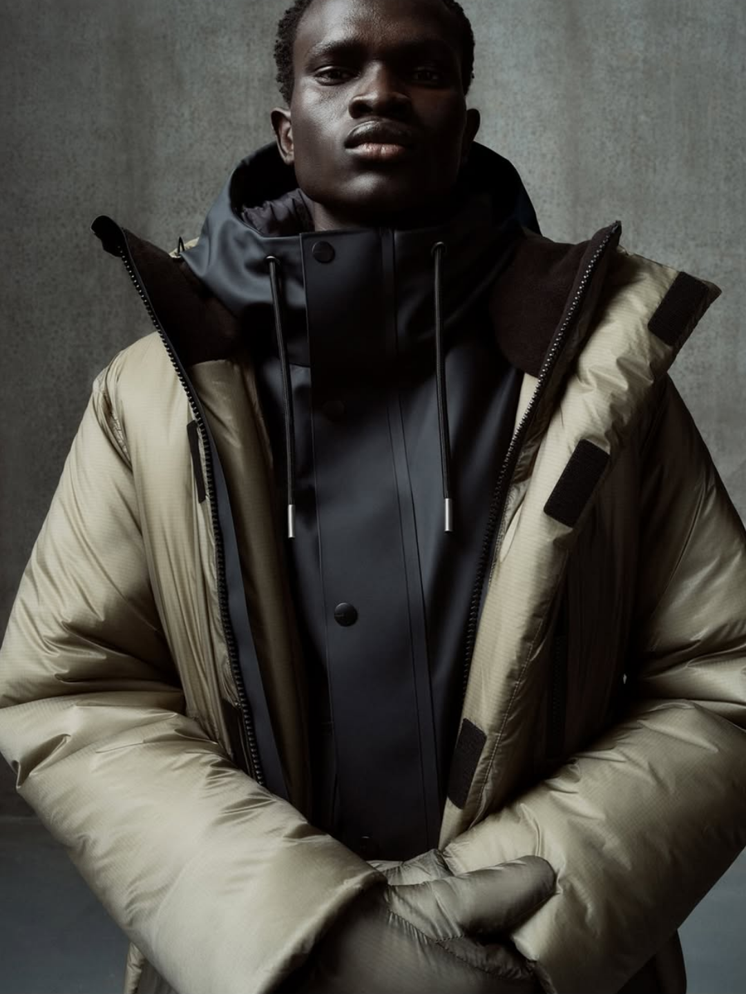 RAINS waterproof parka layered under a padded beige coat — Scandinavian minimalism redefined with functional outerwear built for modern city climates.